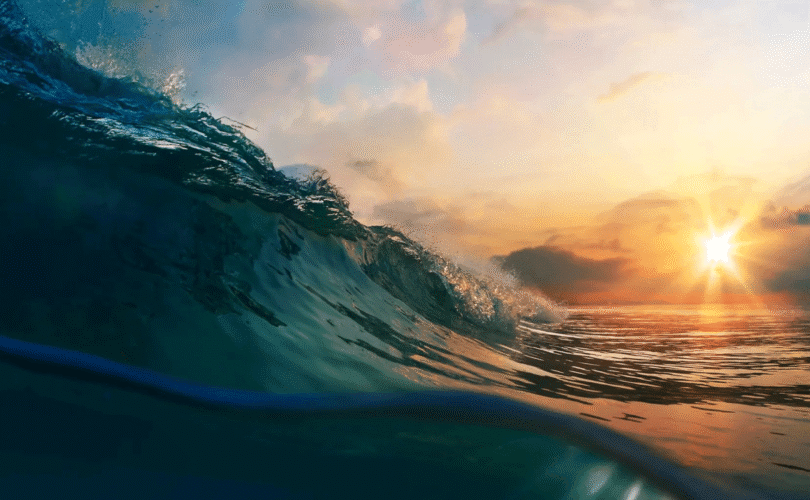 Sunset over the ocean with a rising wave in the foreground, highlighting warming seas amid global climate change concerns.