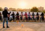 A group of women on motorcycles attend a riding lesson in an open training ground in Karachi while an instructor provides guidance.